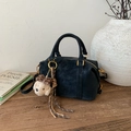 Primer plano de bolso cilíndrico de ante negro con colgante de perro en mesa madera - Negro Con Colgante