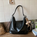 Detail of black soft leather Hobo bag featuring a cute plush bunny charm on a wooden surface - Black With Pendant