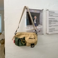 Detail of khaki crossbody bag featuring a green drawstring pocket and black hardware - Yellow