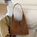 Detailed view of warm brown leopard print suede hobo bag on a white textile sofa - Brown