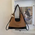 Detailweergave van de bruine suède Hobo-tas met een zwarte lederen basis en een beerbedeltje - Zwart en Bruin met Hanger