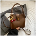 Dettaglio di una borsa a secchiello in pelle marrone con ciondolo a ciliegia su blazer - Stile con Ciondolo a Ciliegia / Marrone con ciondolo