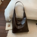 Dettaglio della borsa tote in pelle marrone scuro con tracolla larga e logo goffrato - Marrone