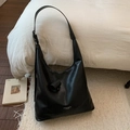 Detailansicht der silbernen Markenbeschriftung auf dem glatten schwarzen Leder der Handtasche - Schwarz