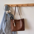 Dettaglio ravvicinato della borsa tote intrecciata marrone con logo e ciondolo di perline - Marrone con Ciondolo