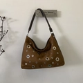 Détail d'un sac bandoulière en daim marron avec œillets métalliques argentés évidés - Marron