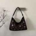 Close-up of retro dark brown suede shoulder bag with decorative silver metal eyelets - Brown