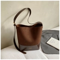 Détail du sac seau en daim marron avec logo doré et boucle de réglage sur la bandoulière - Marron