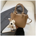 Detail of lychee pattern leather handbag with knotted handle and plush dog charm accessory - Khaki (With Charm)
