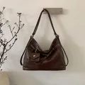 Detalle de bolso hobo de ecocuero marrón oscuro con costuras en contraste y estuche - Marrón