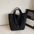 Vista dettagliata del tessuto in nylon nero e logo circolare sulla borsa tote - Nero