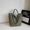 Dettaglio della grande borsa tote in tela verde militare con tasca frontale ed etichetta - Verde