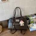 Detail of dark brown leather handbag with silver plaque, plaid ribbon and plush puppy charm - With Charm / Brown