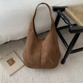 Detail of a large brown suede tote bag on a plush rug in a cozy minimalist home interior - Brown