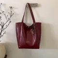Dettaglio della grande borsa tote rosso scuro con finitura lucida e ciondolo a frange - Rosso con Pendente