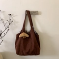 Detail einer braunen Wildleder-Tragetasche mit kariertem Futter und Plüschanhänger - Kaffee mit Anhänger