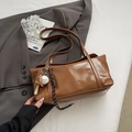 Detalle de bolso de hombro en cuero marrón brillante con logo en relieve y colgante de béisbol - Marrón Barro Con Dije