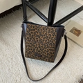 Detail shot of leopard print bucket bag with NO FILTER metal tag on soft carpet - Leopard Print
