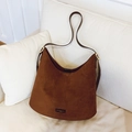 Braune Hobo-Tasche aus Wildleder mit goldener Schnalle auf weißem Sofa - Braun