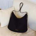 Große Hobo-Eimertasche in Schwarz und Braun im Color-Block-Stil auf beigem Sofa - Schwarz