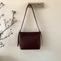 Detail der burgunderroten Leder-Eimertasche an der Wand mit dekorativem Riemen - Weinrot Ohne Anhänger