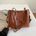 Detalle de bolso retro marrón caramelo con correa tejida ancha y remaches metálicos - Marrón