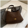 Macro shot of dark brown suede bucket bag featuring a golden oval metal buckle - Brown