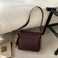 Detail of burgundy leather shoulder bag with cute mushroom charm on white bedding - Wine Red With Pendant
