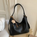 Detail of black vintage tote bag featuring gold logo, side tassel, and plush lamb charm - Black With Pendant