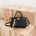 Fashionable black bucket bag with gold lock and decorative charms on stone steps - Black With Pendant