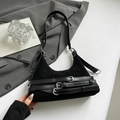 Dettaglio della borsa hobo in camoscio nero con fibbie argentate e cinturini decorativi - Nero