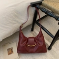 Dettaglio della borsa a mezzaluna rosso scuro con pelle a pieghe e chiusura dorata - Rosso