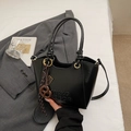 Detail of black bucket bag with knotted handle and 3D embossed texture on leather - Black With Pendant
