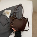 Detail of a dark brown glossy leather bucket bag with embossed logo and metal ring accents - Coffee With Charms