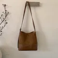 Detailansicht der braunen Wildleder-Beuteltasche mit verstellbarem Gurt und Metallschnalle - Braun