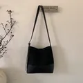 Detailansicht der schwarzen Wildledertasche mit Lederboden und verstellbarem Schultergurt - Schwarz