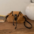 Detailed view of brown suede underarm bag with gold metal buckle on a rustic wooden table - Black and Brown