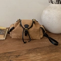 Detailed view of brown matte leather bucket bag with black straps on a wooden table - Black and Khaki