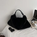 Close-up of fluffy black faux fur tote bag with smooth leather handle and lifestyle props - Black