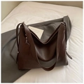 Detalle de bolso tote de cuero marrón oscuro brillante con textura suave y una etiqueta - Marrón