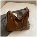 Detalle de un bolso tote de cuero marrón con etiqueta Korea Bags sobre chaqueta gris - Marrón