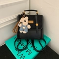 Detalle de mochila mini negra con textura cuero-gamuza y lindo colgante de osito - Negro Con Colgante