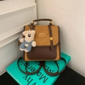 Detalle de la mochila retro de colores en contraste con un colgante de oso de peluche blanco - Marrón con Colgante