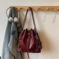 Detail of burgundy drawstring bucket bag with rope charm on a wooden clothes hanger - Red (With Charm)