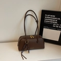 Detailansicht der dunkelbraunen Ledertextur und der goldenen Reißverschlüsse der Handtasche - Mit Anhänger / Kaffeebraun