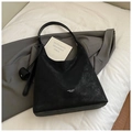 Dettaglio della borsa hobo in pelle opaca nera con texture vintage e ciondolo rotondo - Nero
