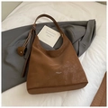 Dettaglio di una borsa tote marrone che mostra la pelle scamosciata e il ciondolo a cuore - Marrone