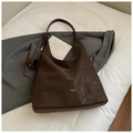 Dettaglio della borsa tote marrone con texture vintage screpolata su sfondo in tessuto bianco - Marrone