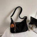 Detail van zwarte canvas Hobo-tas met hondenbedeltje en kwastje op een modern bureau - Zwart Met Hanger