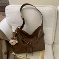 Detail of a brown PU leather tote with bear charm and woven drawstring on a soft sofa - Brown with Pendant
